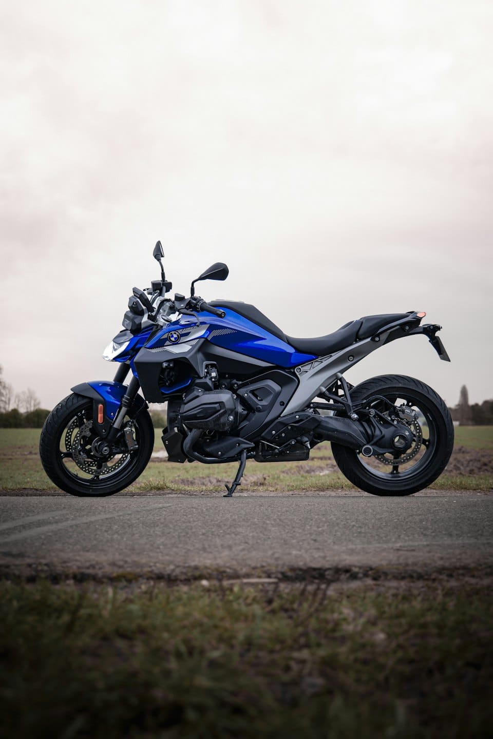 A blue and grey motorcycle parked on a paved road.
