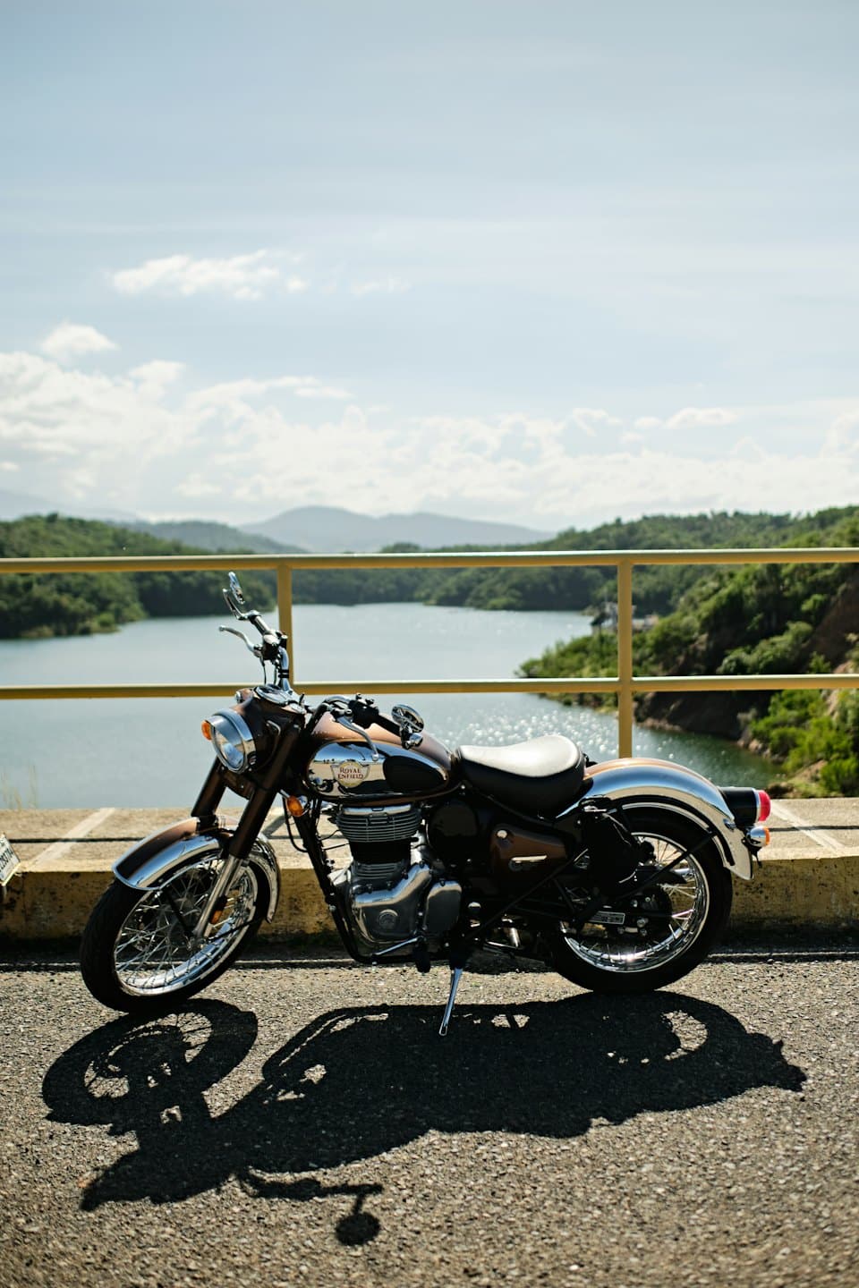 Classic motorcycle parked by a blue lake with green hills.