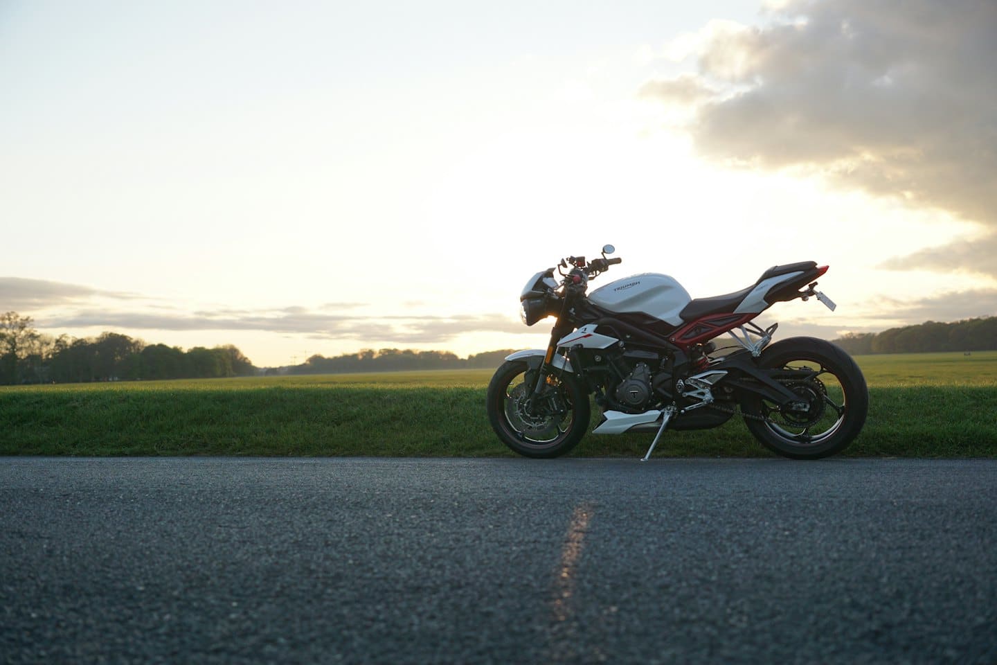 A white and red sports motorcycle parked on a rural road.