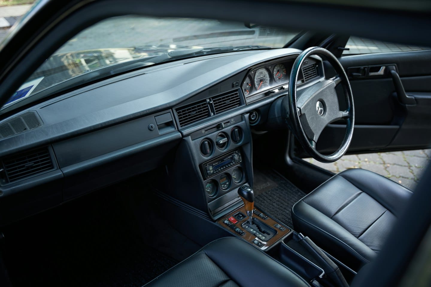 Classic car dashboard and leather interior viewed from the passenger side.